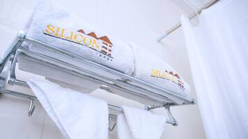 Two white towels with 'Silicon' branding on a metal rack in a bathroom.
