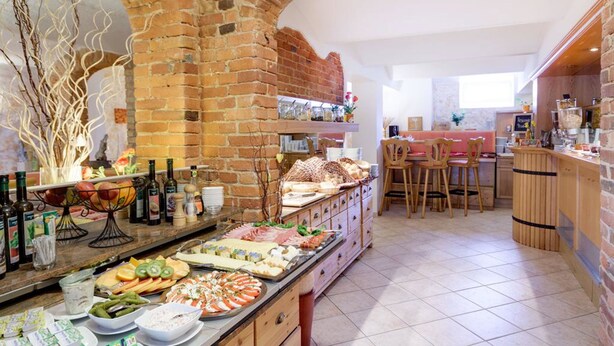 A kitchen with a brick archway, a buffet with various food items, and a bar area with stools. - Parkhotel del Mar (Sassnitz)