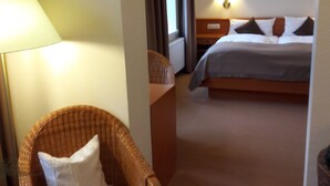 A hotel room with a bed, a chair, a table, and a lamp. - Parkhotel del Mar (Sassnitz)