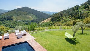 A poolside area with white lounge chairs and a green lawn, overlooking a hilly landscape with vineyards. - Quinta do Bosque (Baiao)