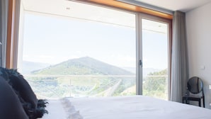 A hotel room with a large bed, a view of a mountain, and a balcony with a railing. - Quinta do Bosque (Baiao)