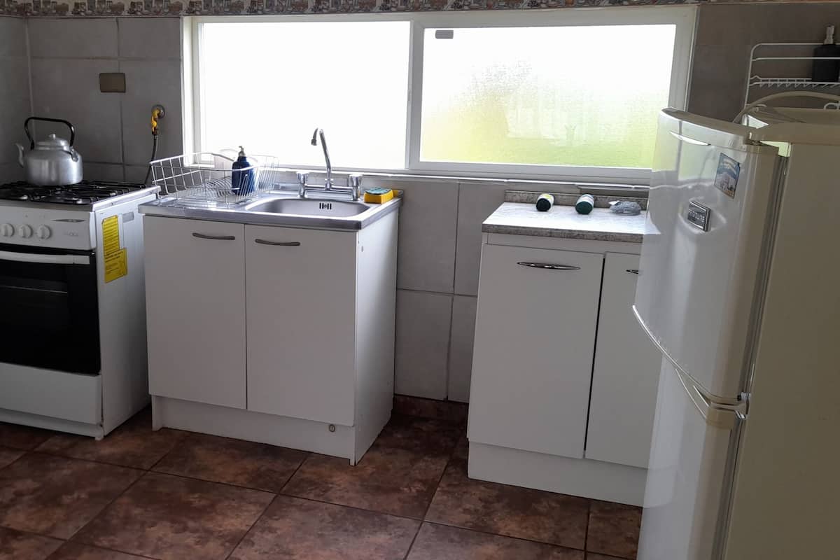 A compact kitchen with a stove, microwave, sink, and refrigerator.