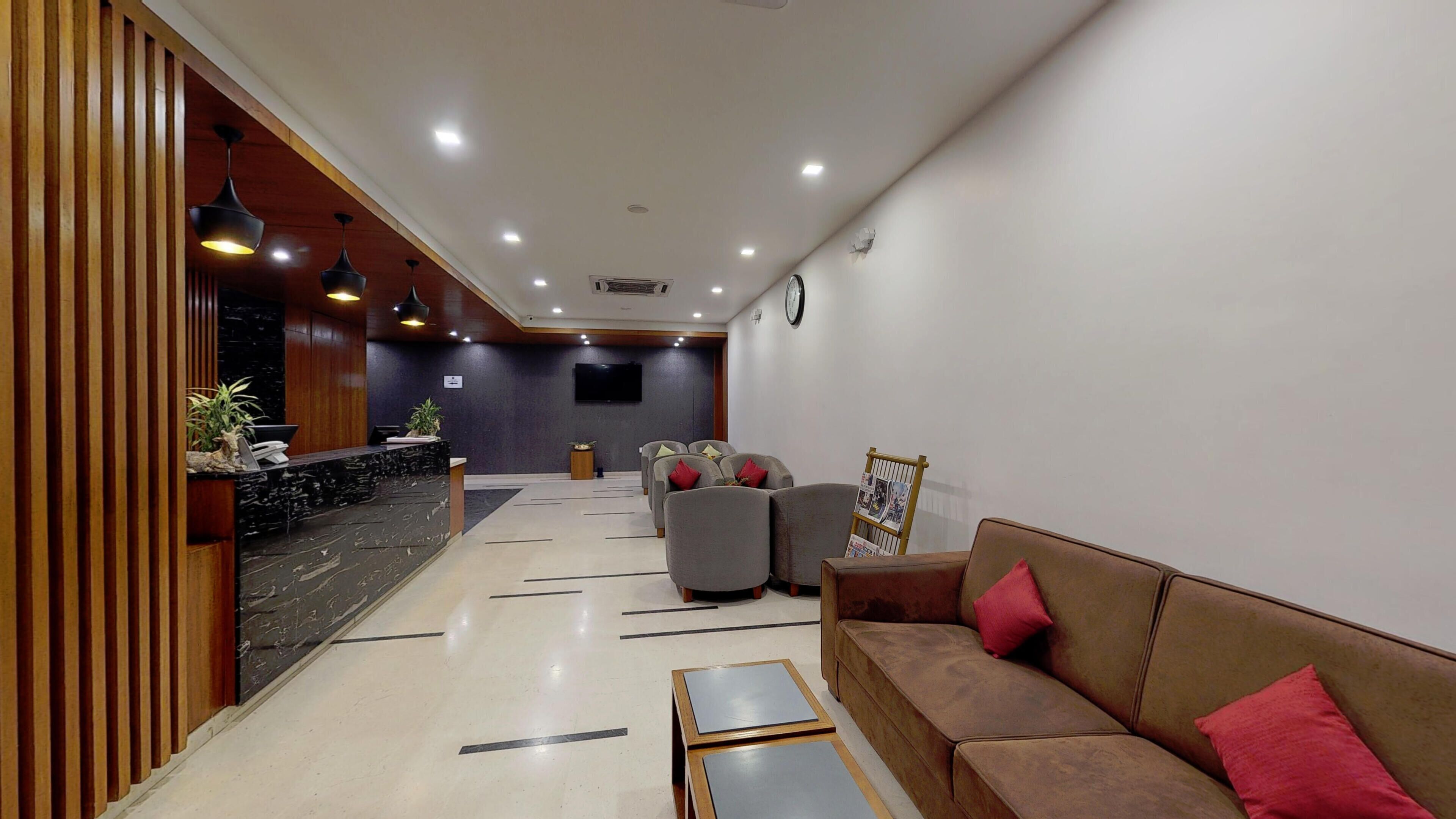 A hotel lobby with a reception desk, seating area, and a clock on the wall.
