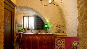 Un couloir étroit avec un mur en pierre, une porte en bois et un comptoir sur lequel se trouve une lampe verte.