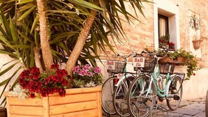 Un bac à fleurs en bois, orné de fleurs, et deux vélos appuyés contre un mur de briques.