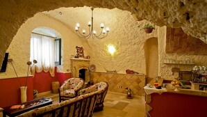 Un intérieur rustique agrémenté d’une arche en pierre, d’un lustre, d’une cheminée et d’un coin cuisine.