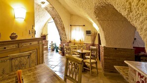 Un coin repas au style rustique, avec des murs en pierre, des meubles en bois et un luminaire à la lumière chaleureuse.