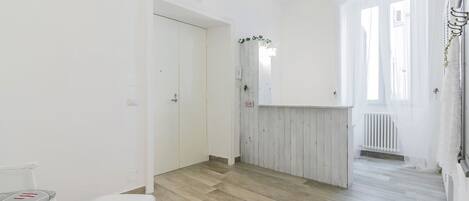 A room with a wooden floor, a white bench, and a white door.