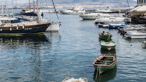 A marina with several boats docked, calm water, and a distant mountain. - Le Villanelle B&B (Naples)