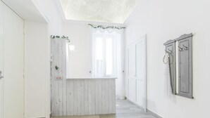 A hallway with a wooden reception desk, a white door, and a wall-mounted coat rack. - Le Villanelle B&B (Naples)