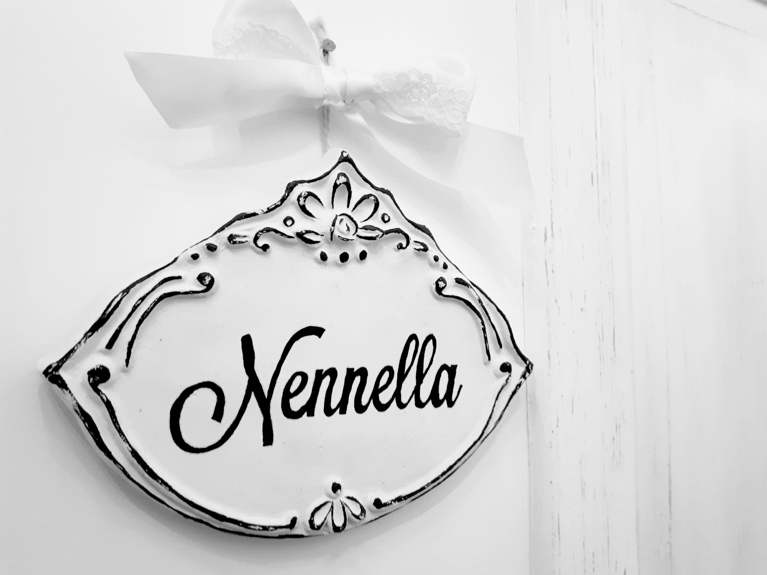 A decorative nameplate with the name "Nennella" on a white background.