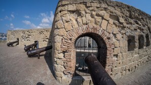 An ancient stone structure with a large arched entrance, featuring rusted cannons and a metal gate. - Le Villanelle B&B (Naples)