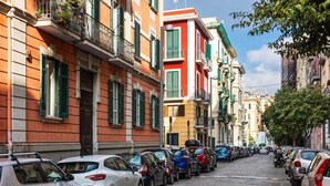 A cobblestone street lined with parked cars and colorful buildings with balconies. - B&B Colori e Note (Naples)