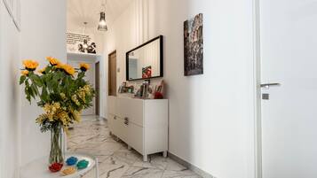 A hallway with a white dresser, a mirror, and a vase of flowers.
