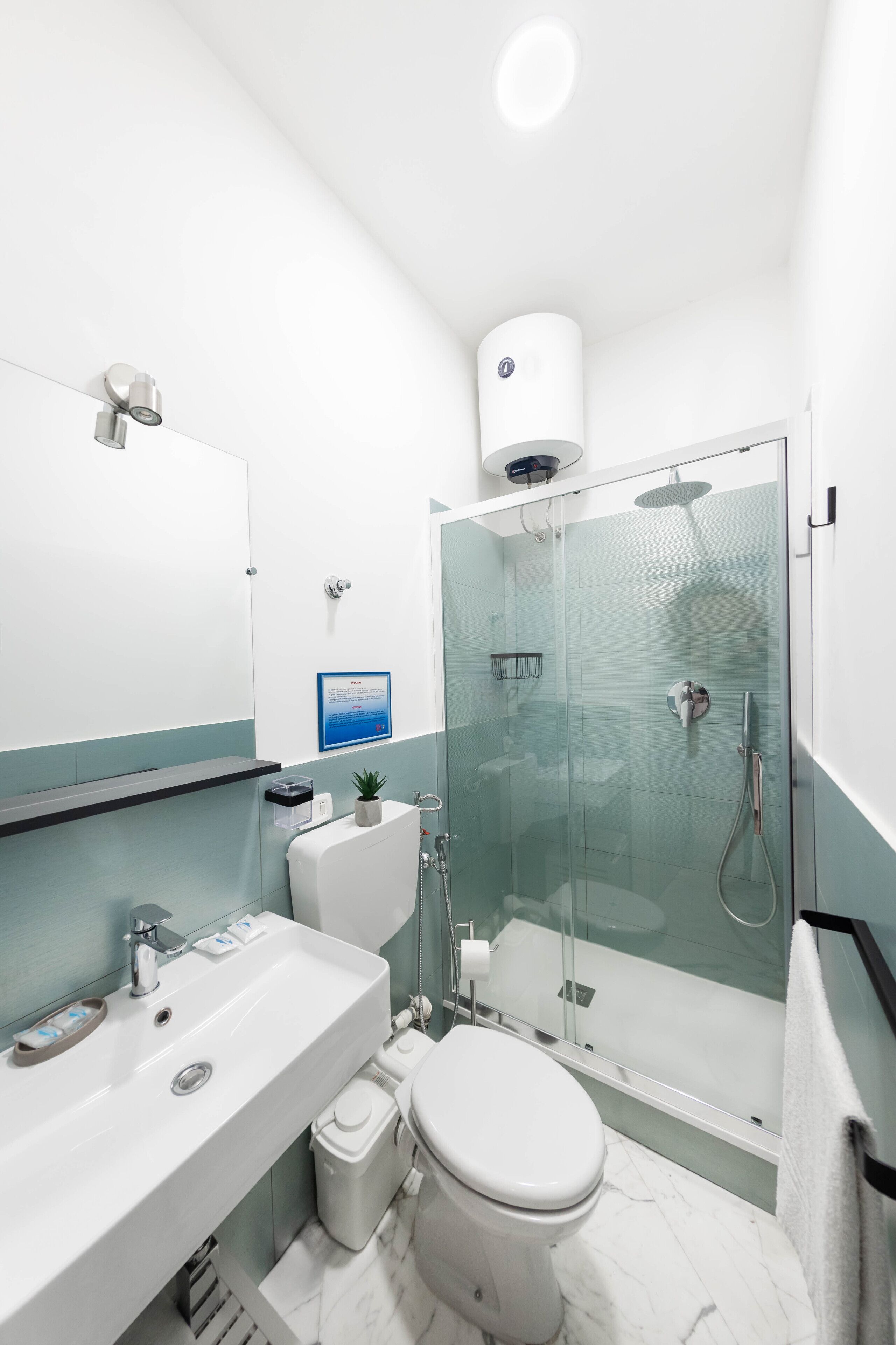 A modern bathroom with a glass-enclosed shower, a white sink, and a toilet.