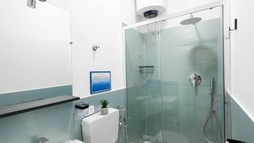 A modern bathroom with a glass-enclosed shower, a white sink, and a toilet.