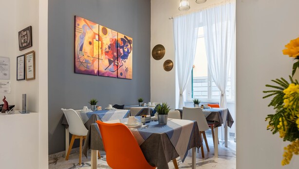 A dining area with a large abstract painting, multiple tables, and chairs. - B&B Colori e Note (Naples)