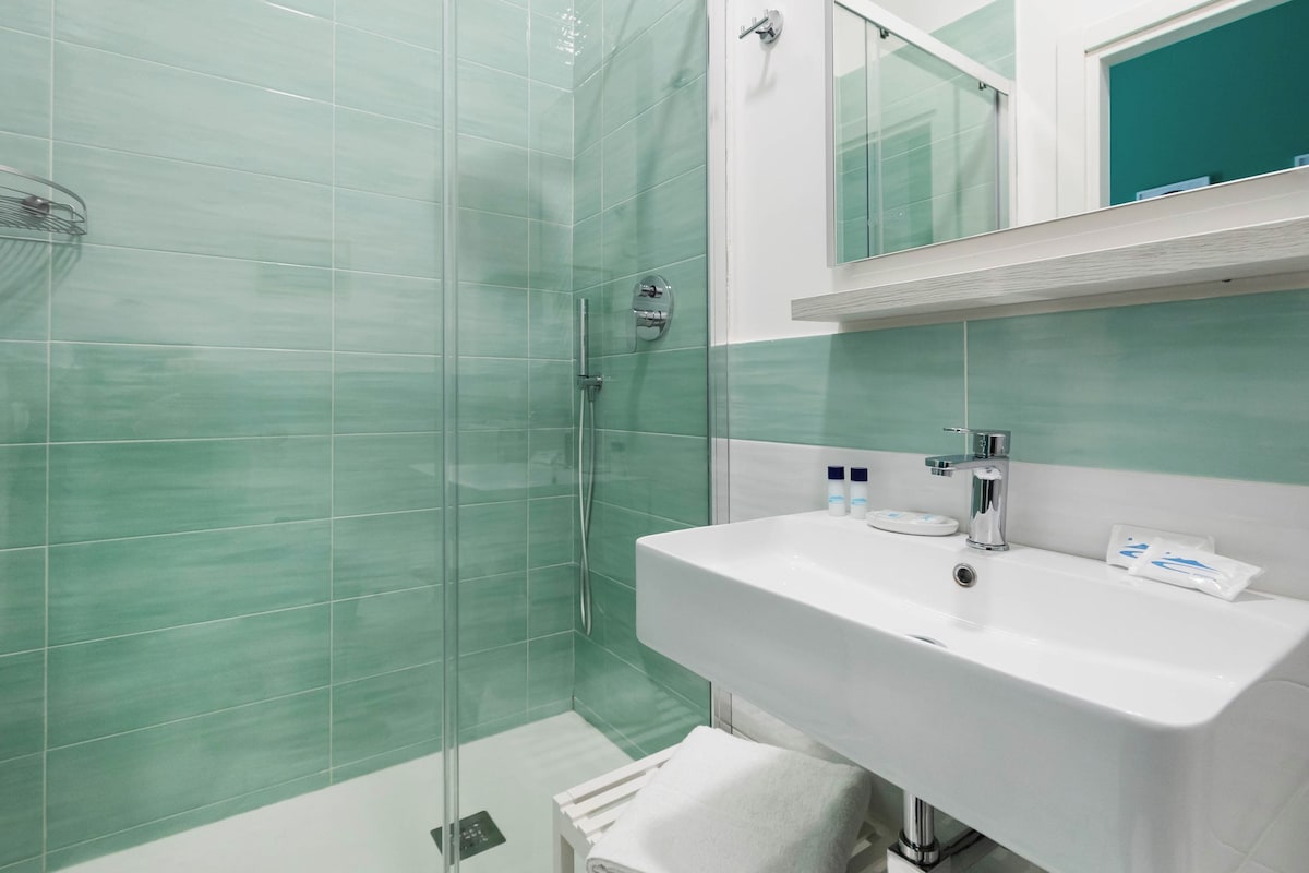 A modern bathroom with a glass-enclosed shower, a white sink, and a mirror above it.