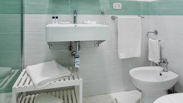 Casa de banho com lavatório branco, sanita branca e cabine de duche em vidro.