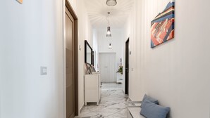 A hallway with a white bench, a white dresser, and a painting on the wall. - B&B Colori e Note (Naples)