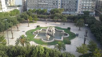 A public square with a central fountain, surrounded by trees and buildings.
