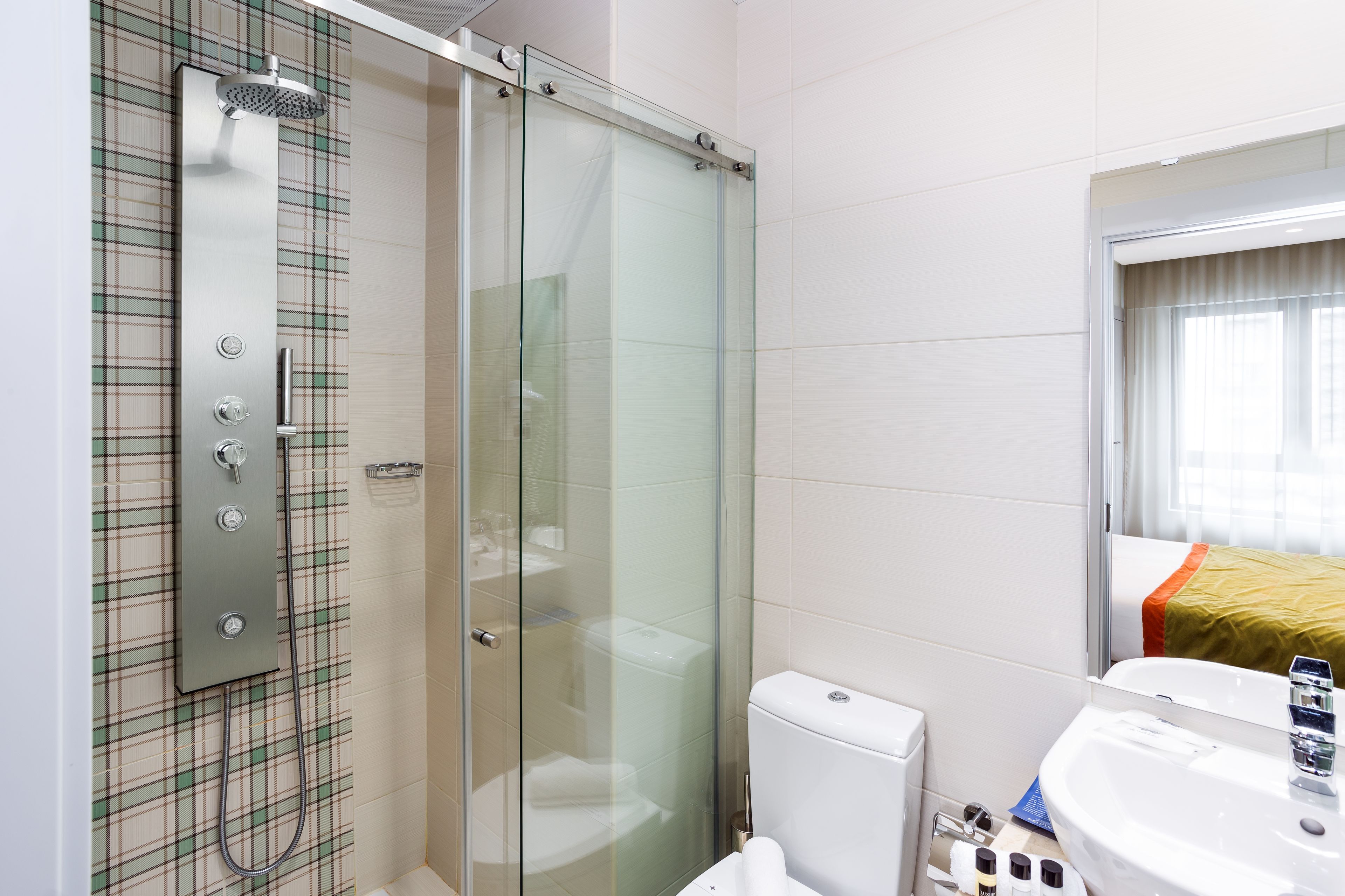 A modern bathroom with a glass-enclosed shower, a toilet, and a sink with a mirror.