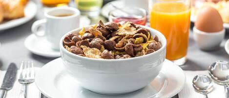 A breakfast setting with a bowl of cereal, a glass of orange juice, and a cup of coffee.