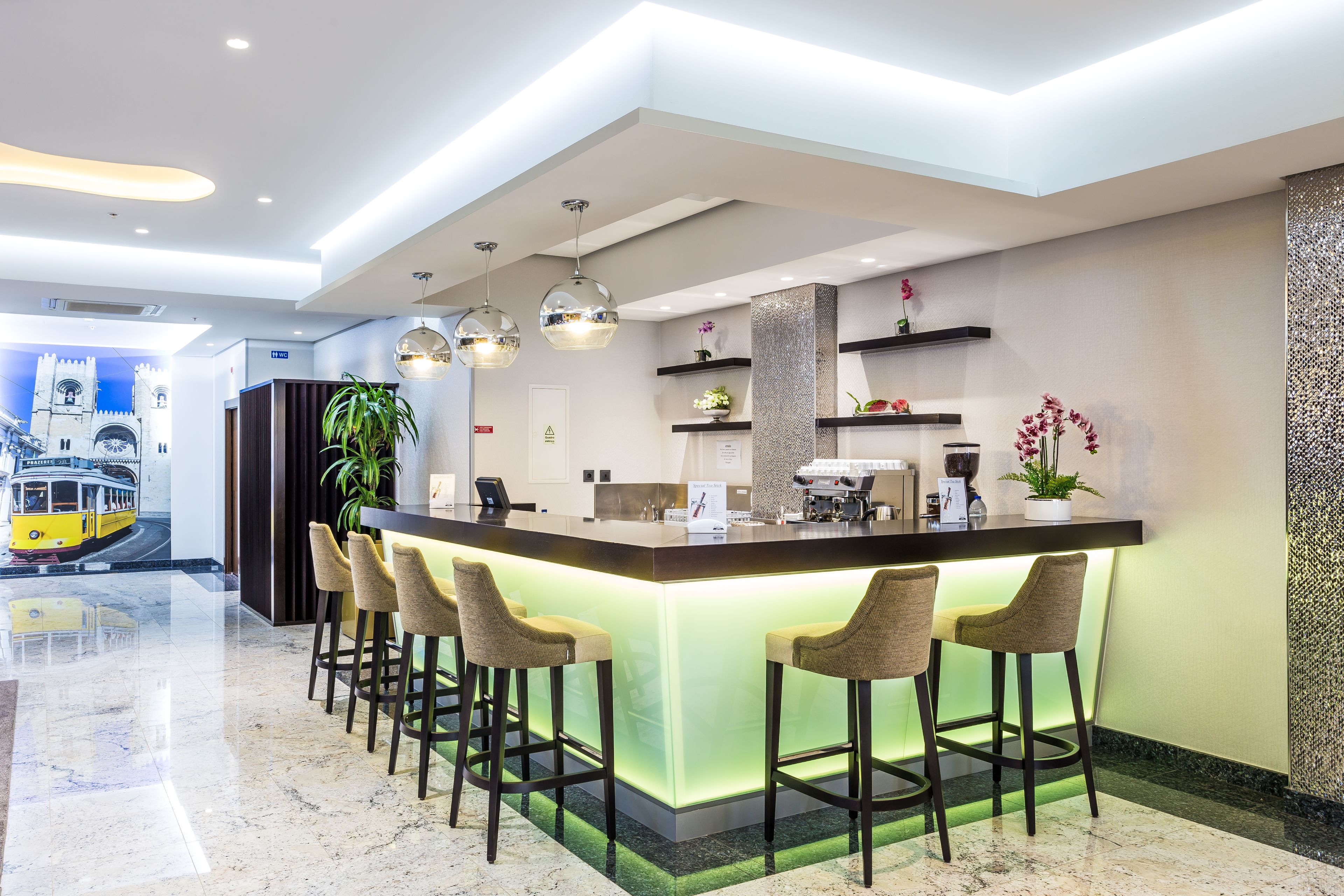 Un área de bar moderna con una barra alargada, taburetes y una iluminación ambiental.