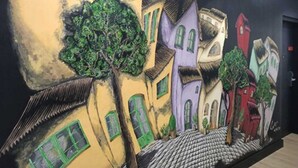 A mural of colorful buildings with green windows and trees. - Apartamentos Mayerling Bisbe Urquinaona (Barcelona)