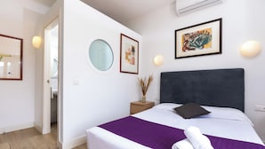 A modern hotel room with a large bed, a round mirror, and artwork on the walls. - Apartamentos Mayerling Bisbe Urquinaona (Barcelona)