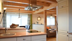 Une cuisine moderne avec des poutres en bois, une cuisinière encastrée et un grand îlot central doté d’un évier.