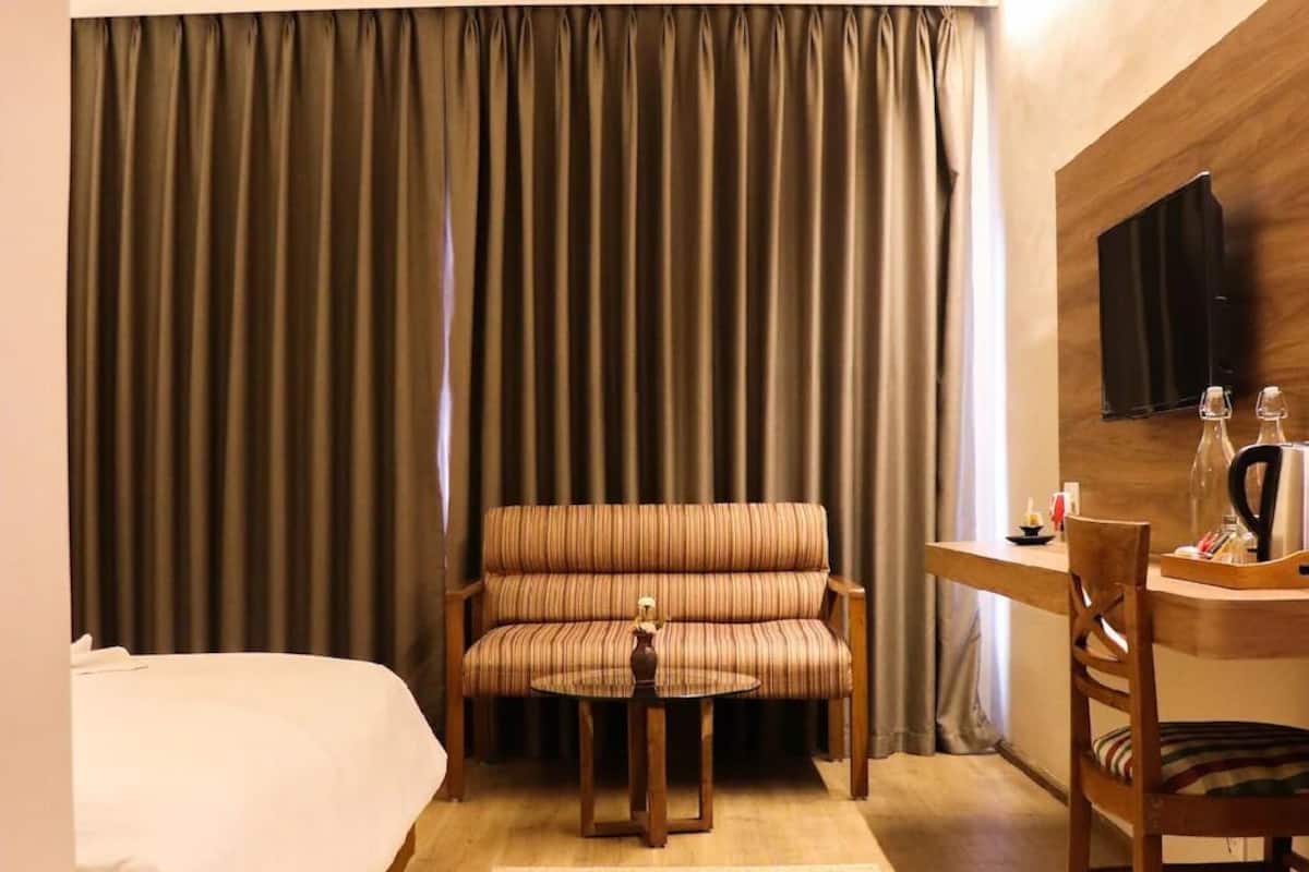 Une chambre d’hôtel avec un lit, un canapé, une petite table avec une chaise, une télévision et un mur en bois.