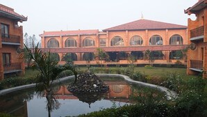 A courtyard with a central pond, surrounded by brick buildings with arched windows and balconies.