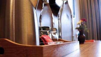 A wooden tray with a stainless steel kettle and two glass bottles on a wooden table.