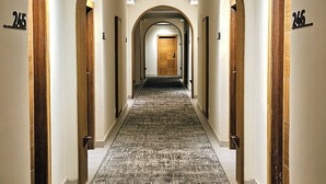 A hotel hallway with a carpeted floor, wooden door frames, and numbered doors.