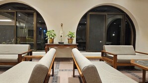 A lobby with two sofas, a wooden table, and potted plants.