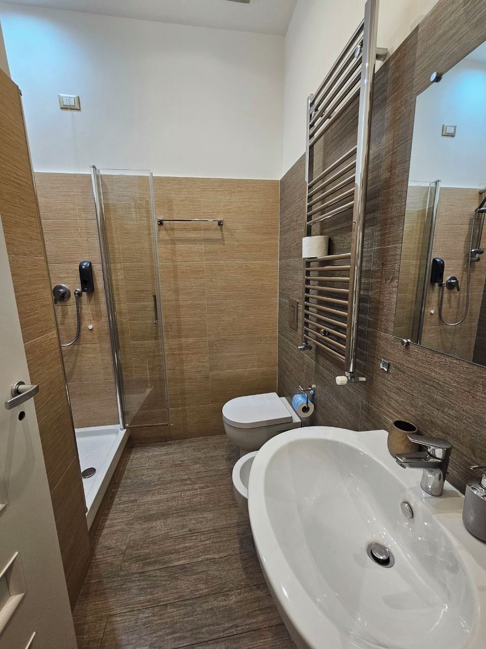 A modern bathroom with a glass-enclosed shower, a toilet, and a large sink.