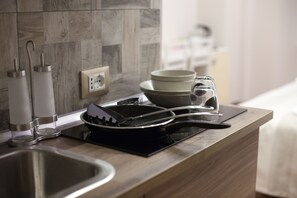 A modern kitchen with a stainless steel sink, a black induction cooktop, and a wooden countertop. - Maison Imperiale (Rome)