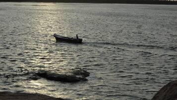 A calm body of water with a small boat and a person rowing.