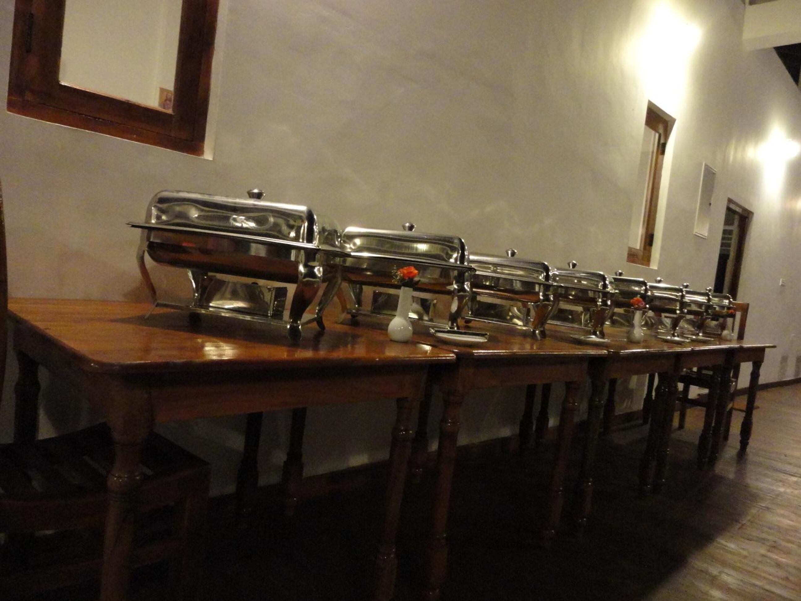A buffet setup with multiple serving stations, wooden tables, and chairs.