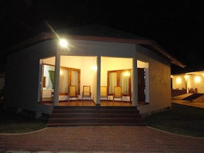 A two-story building with a covered outdoor seating area and a staircase leading to the upper floor. - Hotel Naaval (Manmunai North)
