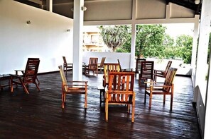 A spacious indoor area with wooden chairs and tables arranged for seating. - Hotel Naaval (Manmunai North)