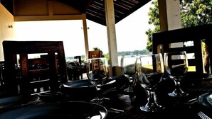 Un espacio al aire libre con mesas dispuestas para comer, sillas y copas de vino.