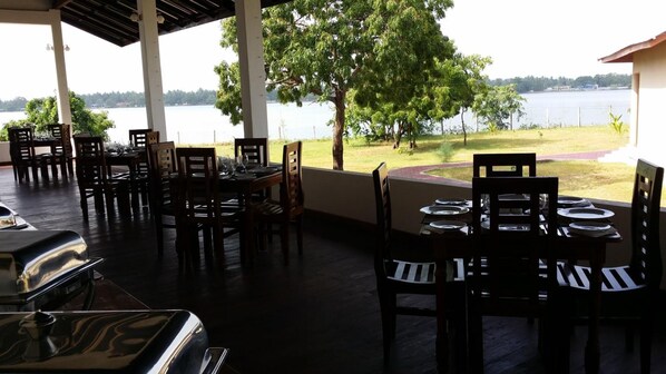 Un área de comedor al aire libre con mesas y sillas, con vistas a un lago.