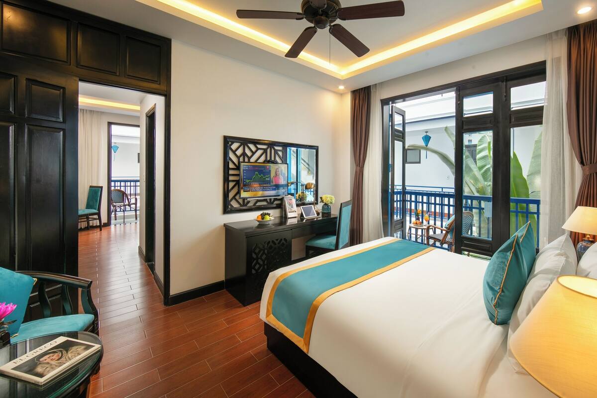 Habitación de hotel con una cama grande, un escritorio y un balcón con vistas.
