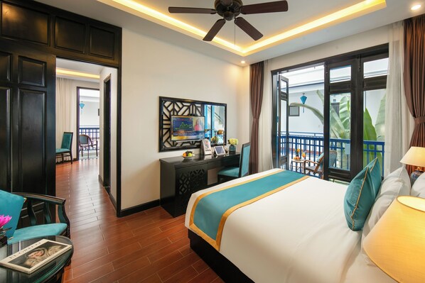 A hotel room with a large bed, a desk, and a balcony with a view. - Silk River Hoi An Retreat (Da Nang)