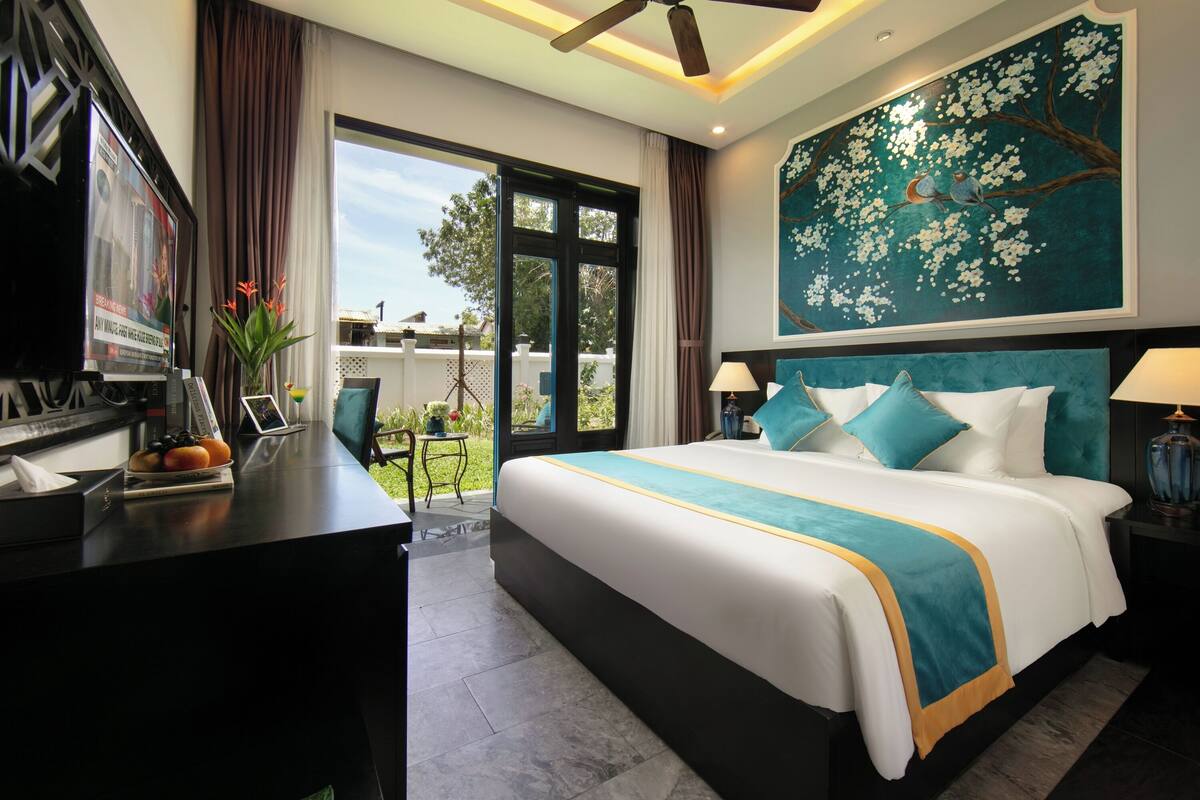 Una habitación de hotel con una cama grande, un escritorio con televisor y vistas al exterior.