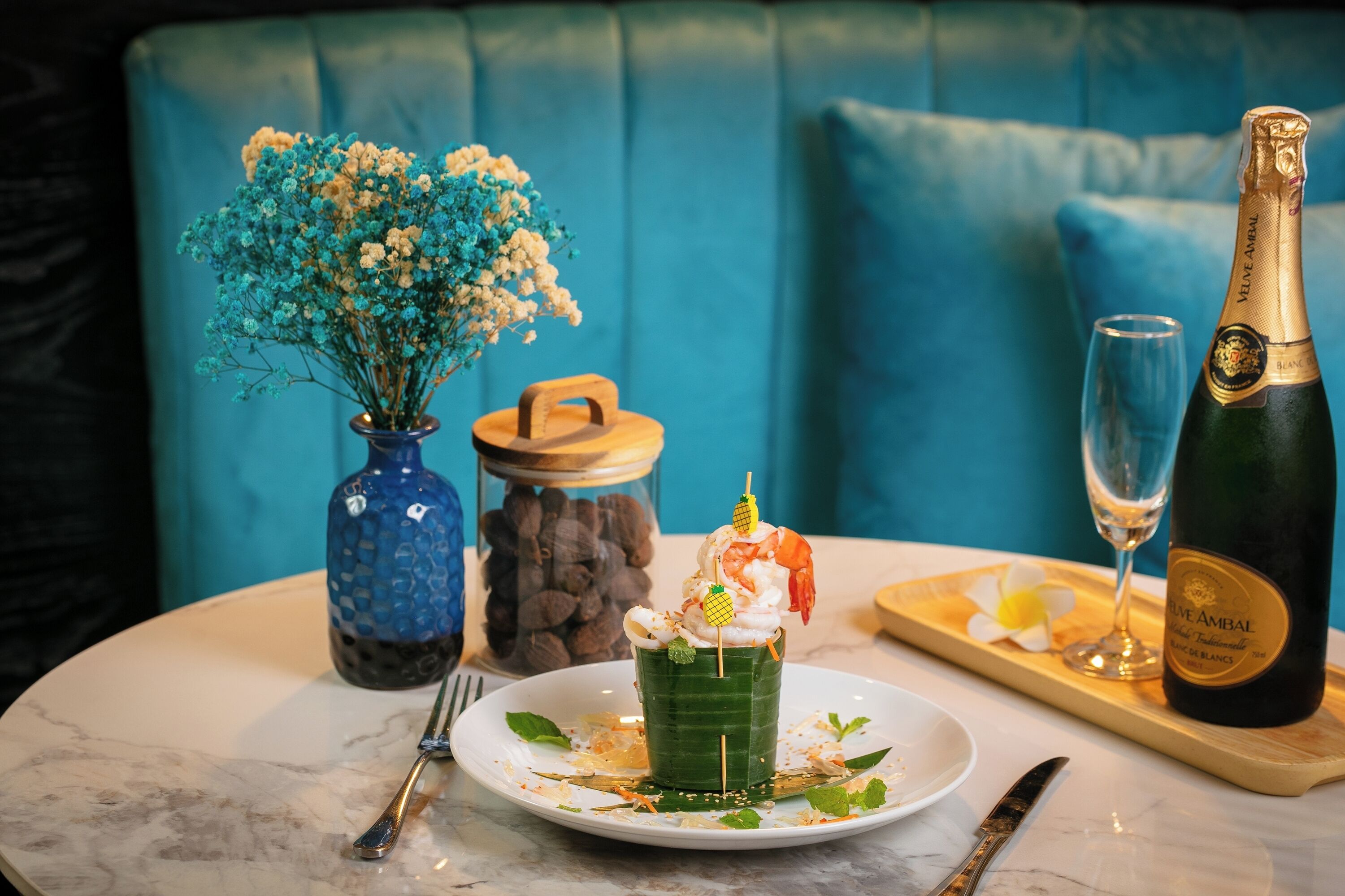 Ein Tisch mit Dessert, einer Champagnerflasche und einer Blumenvase.