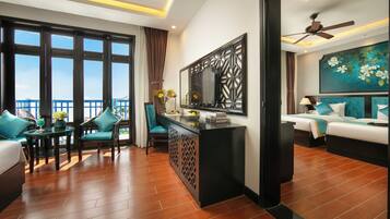 A hotel room with a balcony, a dining area with chairs and a table, and a bedroom with a bed and a painting.