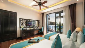 A hotel room with two beds, a desk, a TV, and a balcony view. - Silk River Hoi An Retreat (Da Nang)